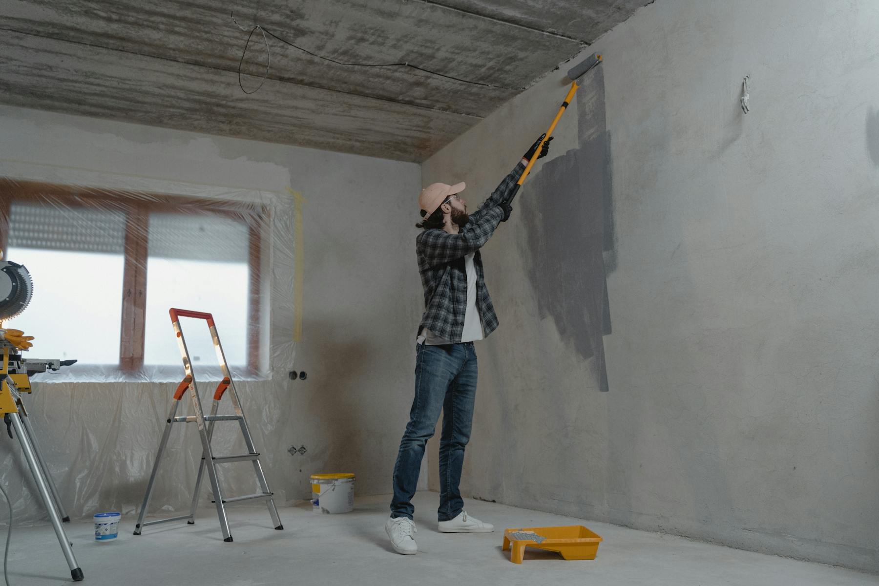 Contractor preparing and painting an interior wall